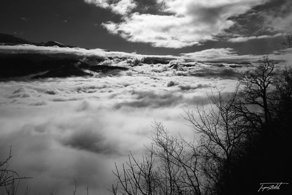 photographie de la montagne au dessus des nuages en noir et blanc